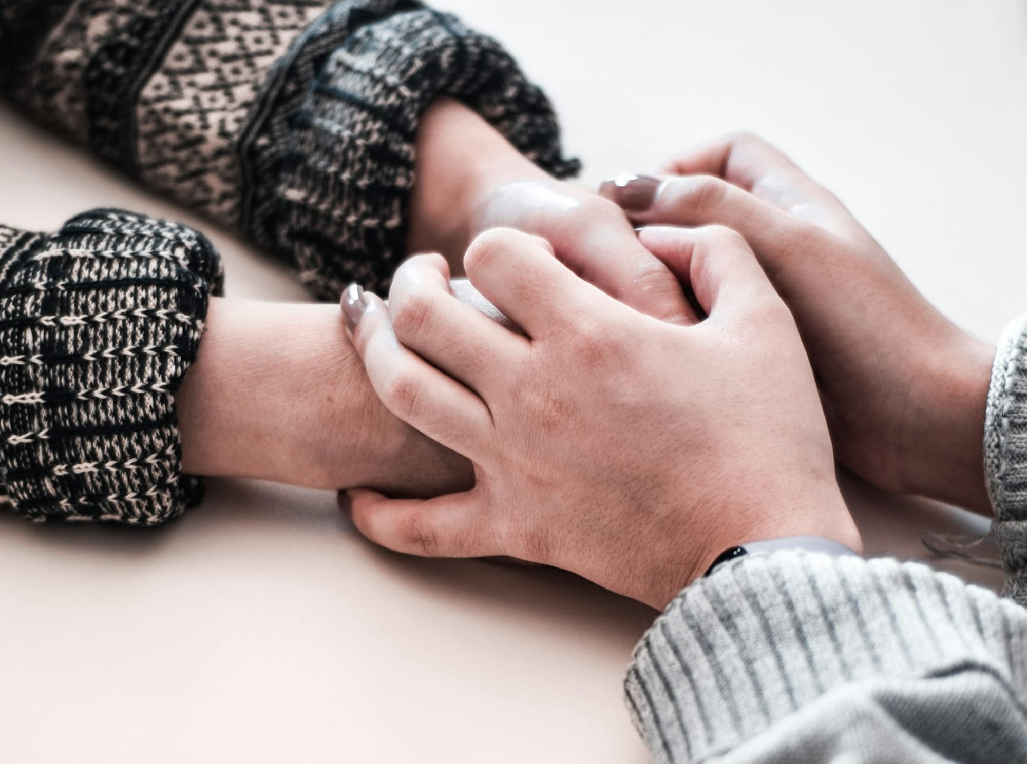 Due mani che si sfiorano con delicatezza sopra un tavolo, gesto di cura e consenso