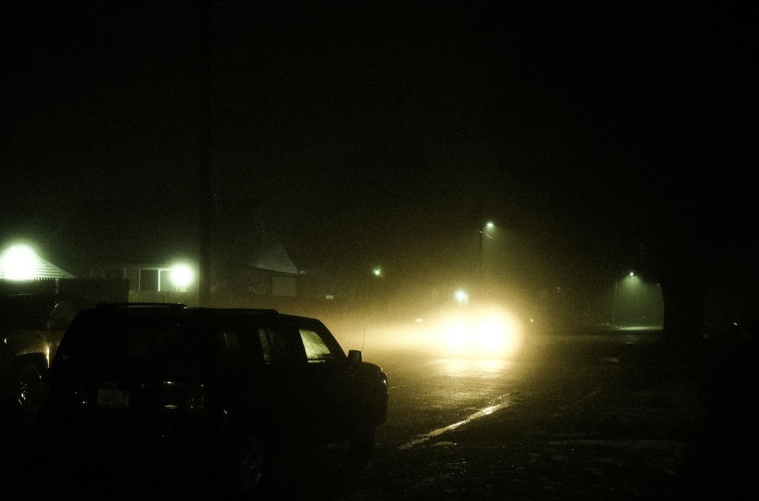 a couple of cars driving down a street at night