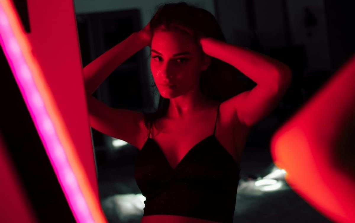 Persona in lingerie nera che tiene un tessuto rosso, in un gesto sensuale e consapevole